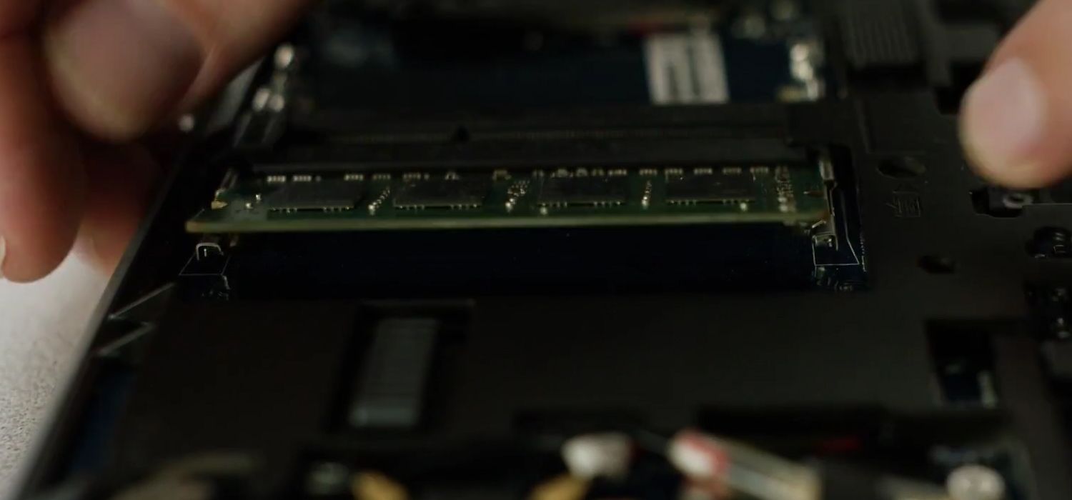 Una persona quita los clips laterales de un módulo Crucial de RAM para retirarlo de un ordenador portátil